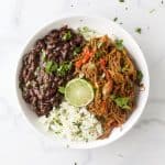 crock pot ropa vieja recipe (cuban shredded beef) in a bowl with rice and beans