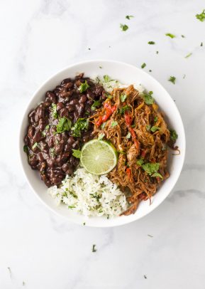 crock pot ropa vieja recipe (cuban shredded beef) in a bowl with rice and beans