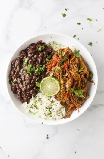 crock pot ropa vieja recipe (cuban shredded beef) in a bowl with rice and beans