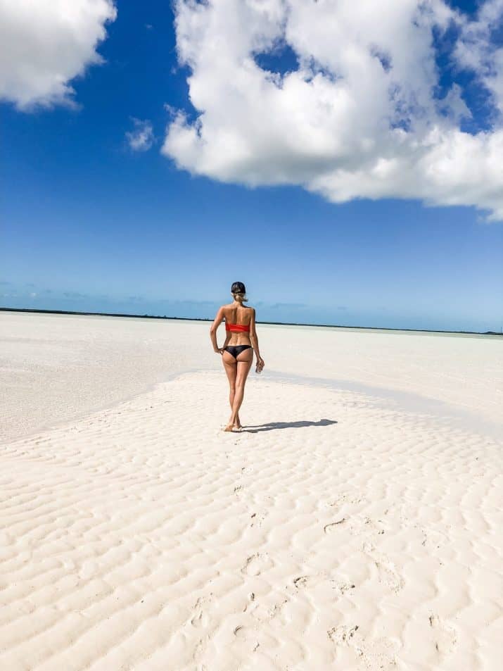 photo of a girl from behind on a long sandbar surrounded by water