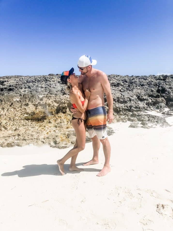 photo of a couple laughing in front of a blow hole in the bahamas