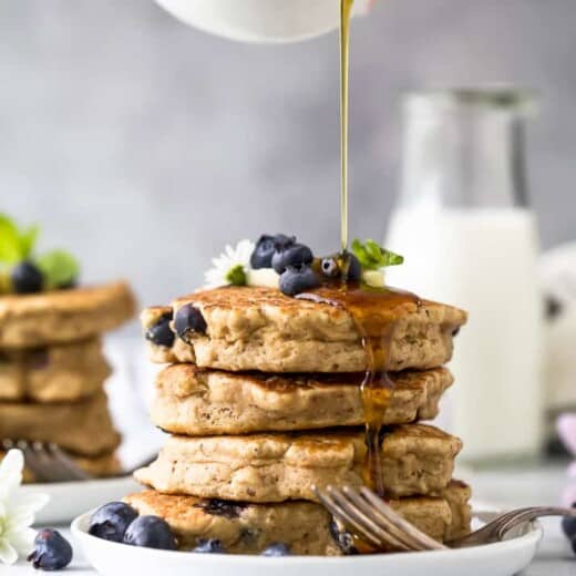 stack of healthy vegan blueberry pancakes with syrup being poured over them