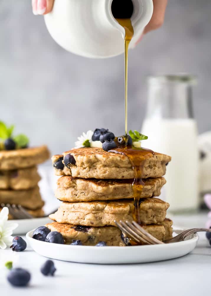 Stack of healthy vegan blueberry pancakes with syrup poured over them