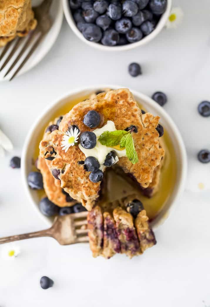 overhead photo of healthy vegan blueberry pancakes on a plate with butter on top