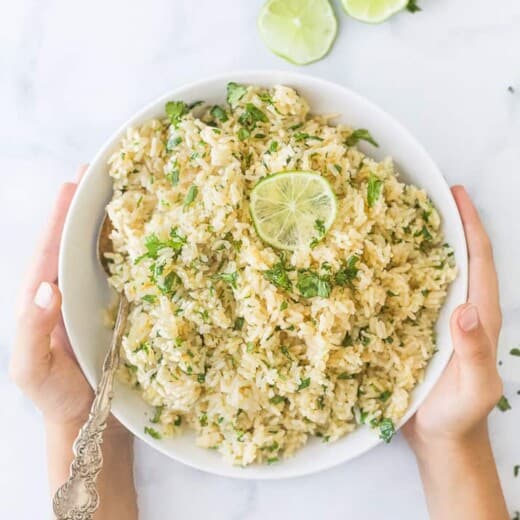 the best instant pot cilantro lime rice in a bowl with hands holding the bowl
