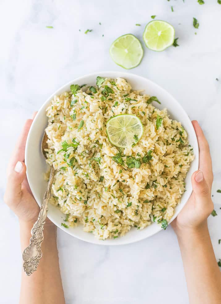 the best instant pot cilantro lime rice in a bowl with hands holding the bowl