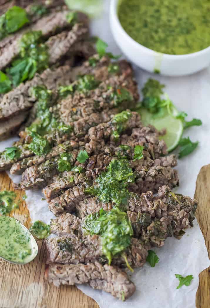 the best marinated grilled flank steak on a cutting board with chimichurri sauce