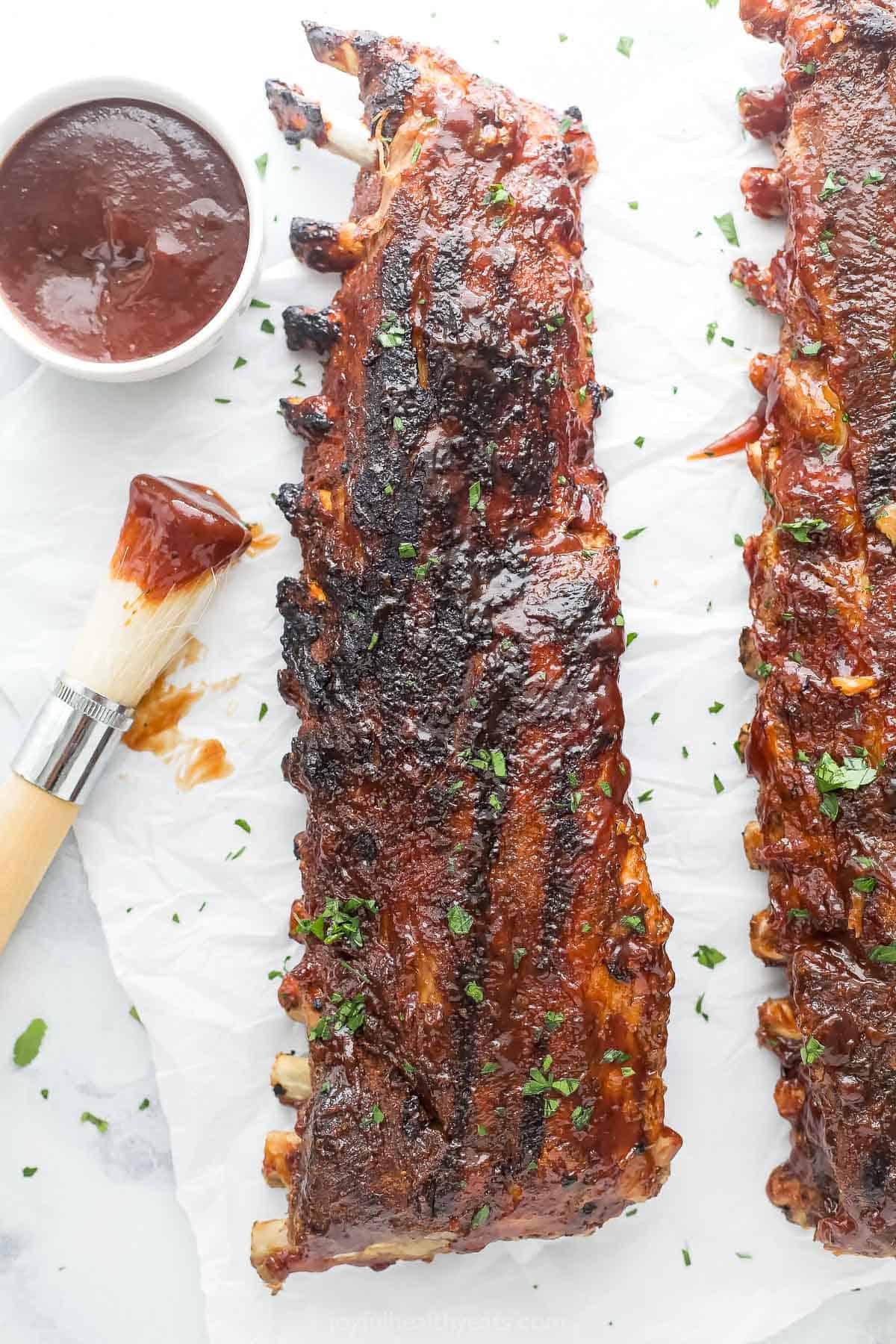 This fall-of-the-bone baby back rib recipe will be a favorite of July 4, with garlic-synamon spice rubs and BBQs Glass. The ribs behind the playful baby with more BBQ sauce on the side.