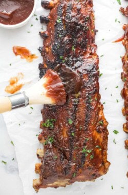 Brushing more BBQ sauce on the grilled ribs.