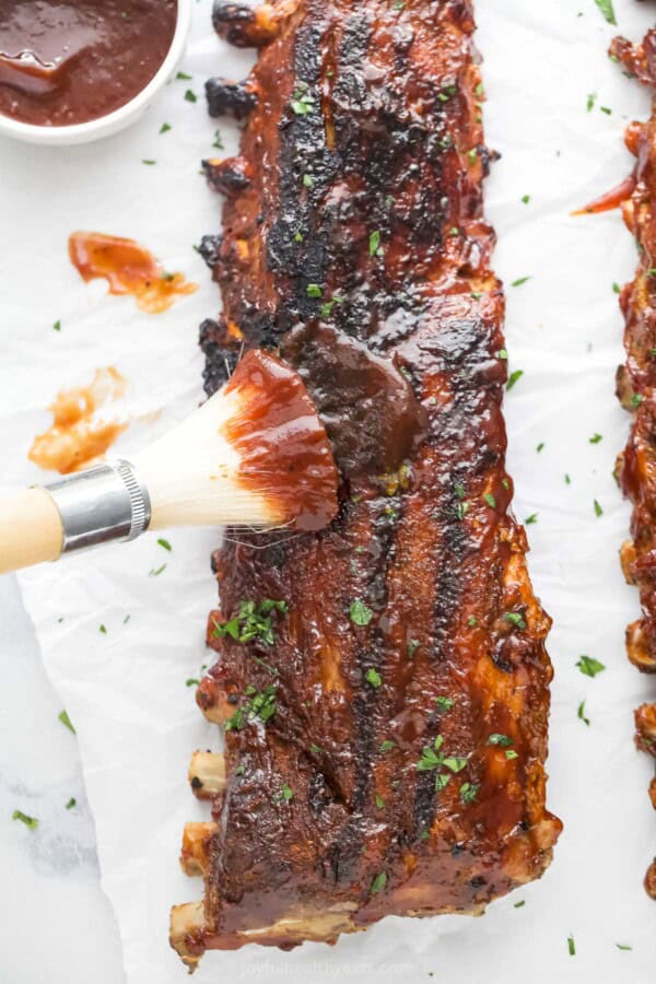 Brushing more BBQ sauce on the grilled ribs.