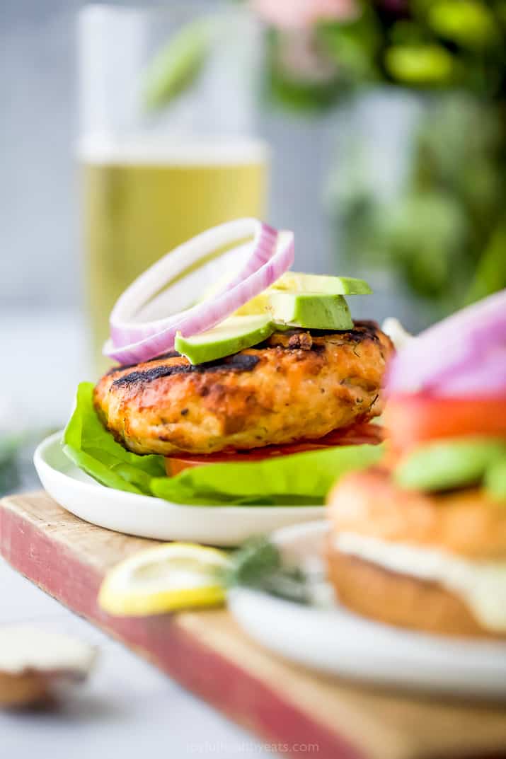 grilled salmon burger with tomato, onion and avocado on a lettuce cup