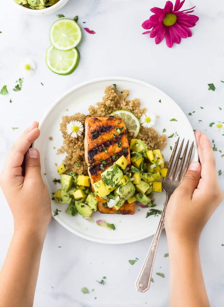 chili lime grilled salmon with mango avocado salsa on a plate with hands holding the plate