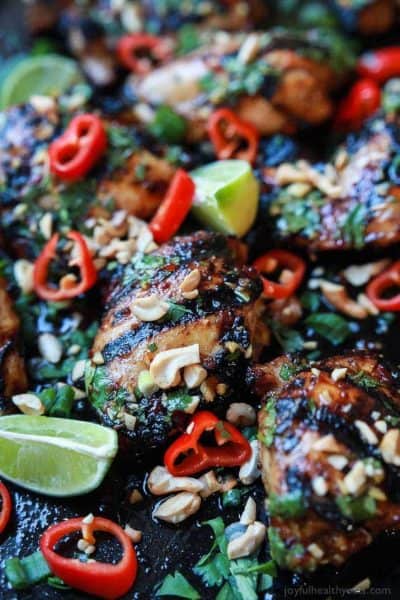 spicy thai grilled chicken thighs with limes and peppers on a baking sheet
