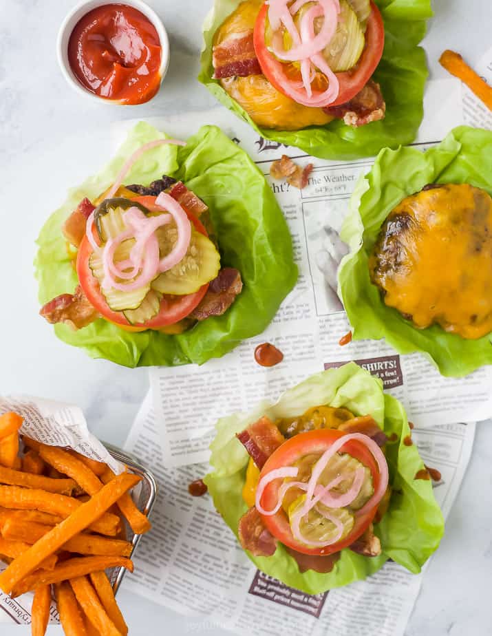 overhead photo of keto bacon cheeseburgers on a lettuce cup with sweet potato fries