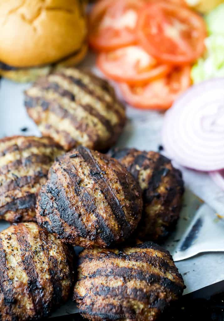 grilled turkey burgers on a baking sheet with all the burger fixings