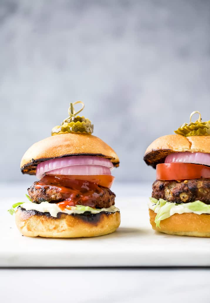 the ultimate classic turkey burgers on a cutting board with all the toppings