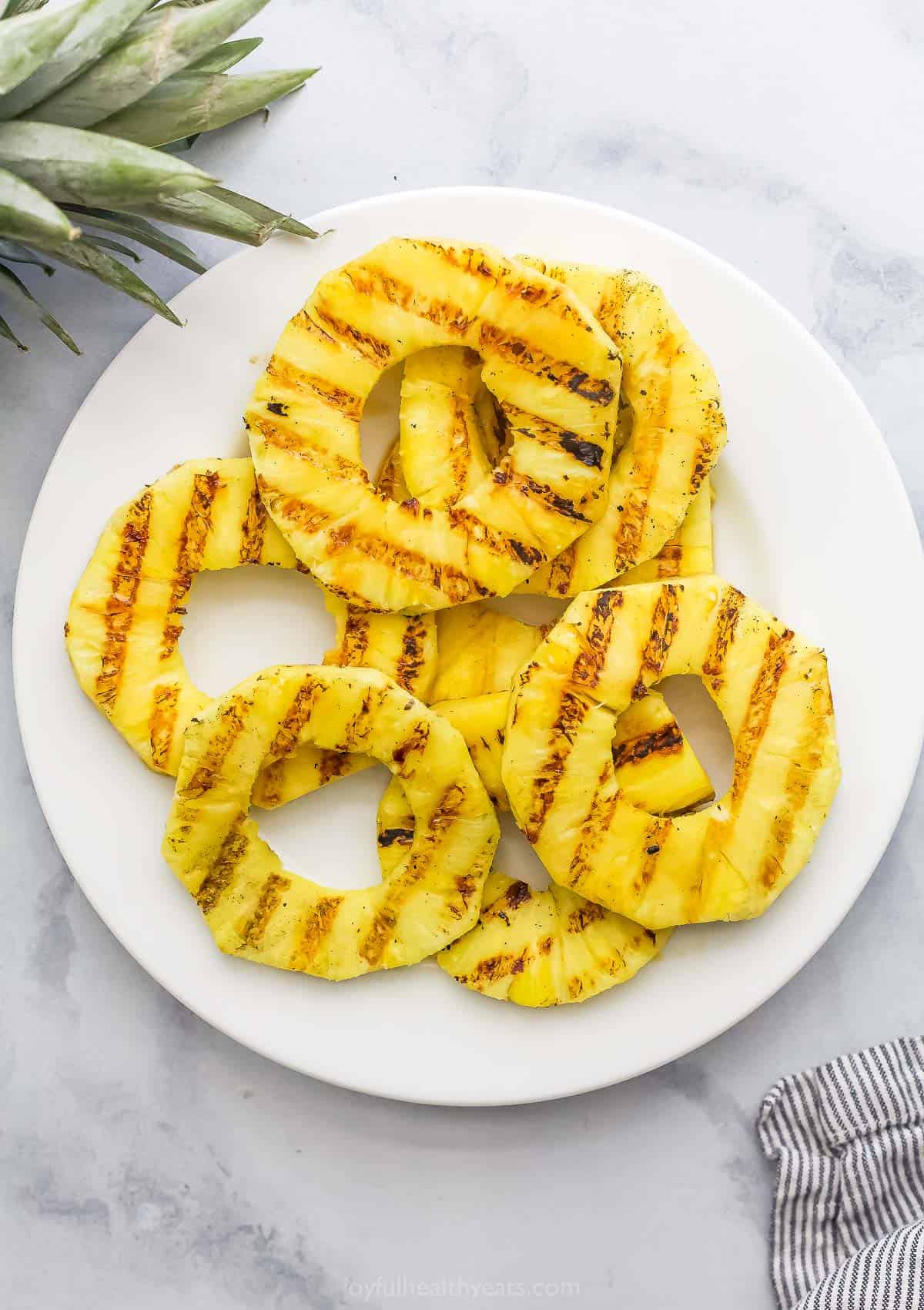 Juicy Grilled Pineapple is the easiest summer dessert and also the tastiest! Serve it as-is or fancy it up with a scoop of ice cream. Overhead view of grilled pineapple on plate