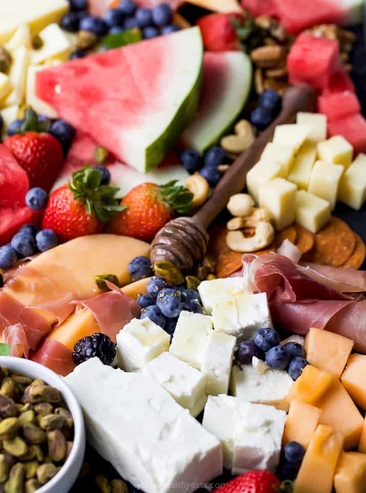 close up of summer cheese board with fruit honey and cheeses