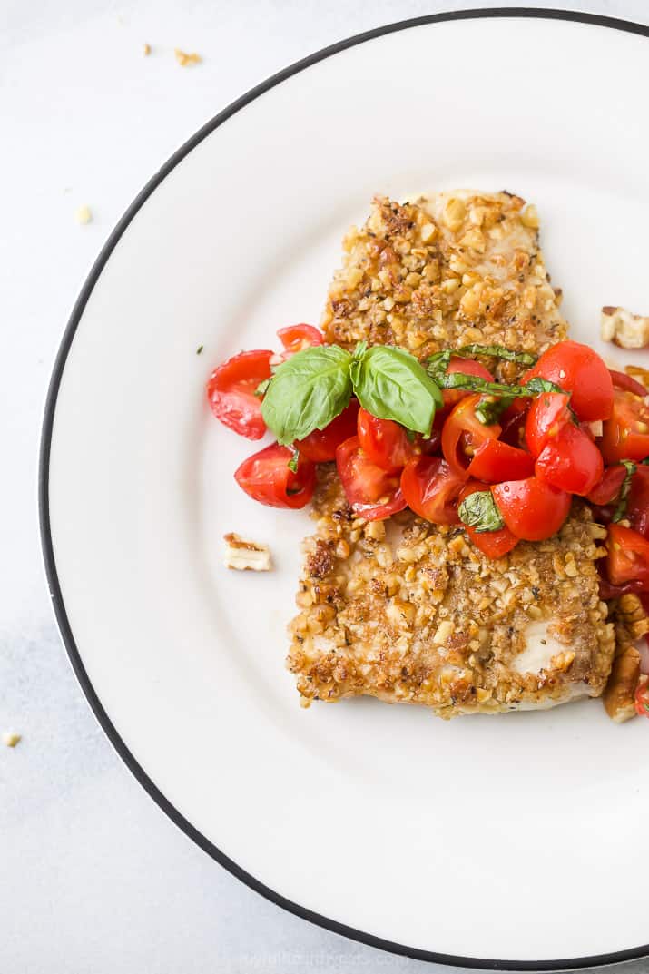 overhead photo of pecan crusted tilapia on a plate with tomato bruschetta