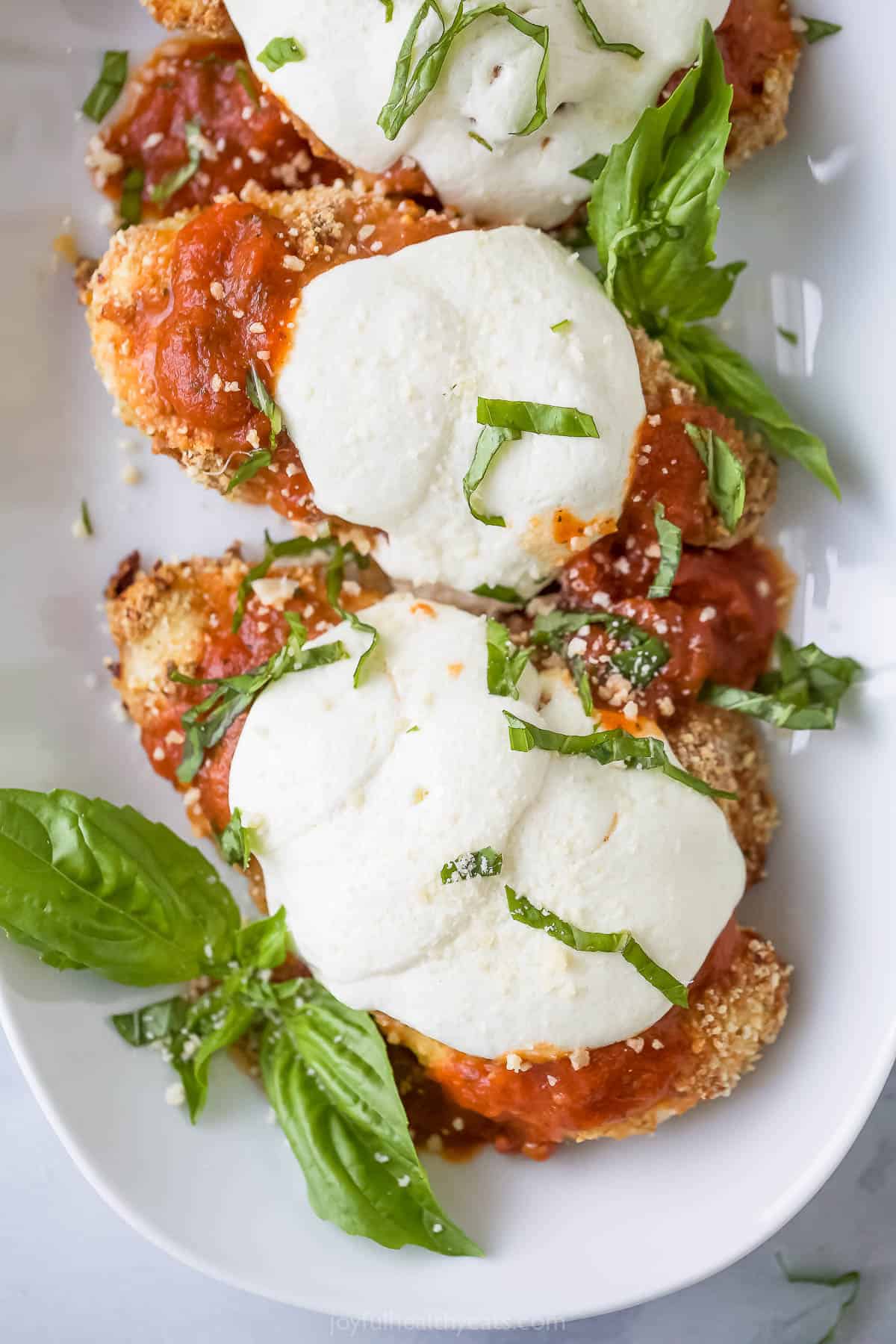 Two baked chicken parmesan pieces on a plate. 