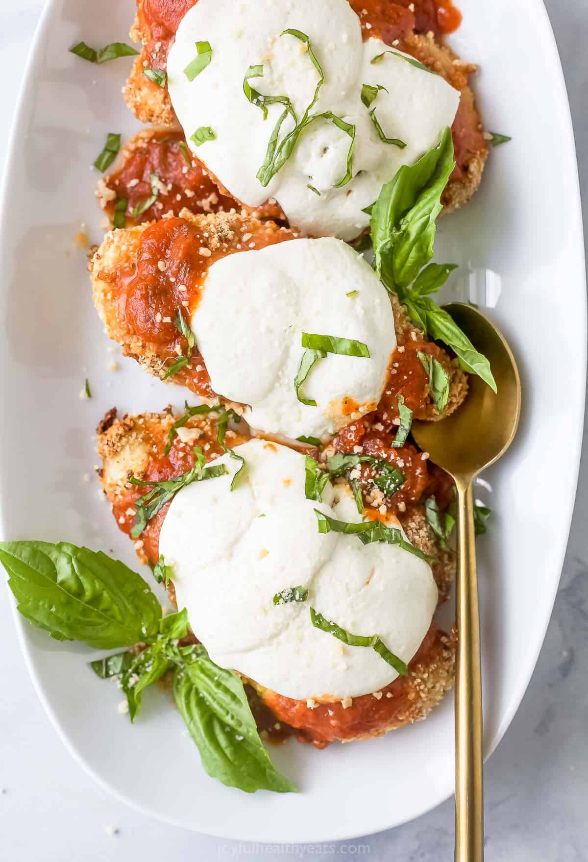 Three pieces of chicken parm with fresh basil. 