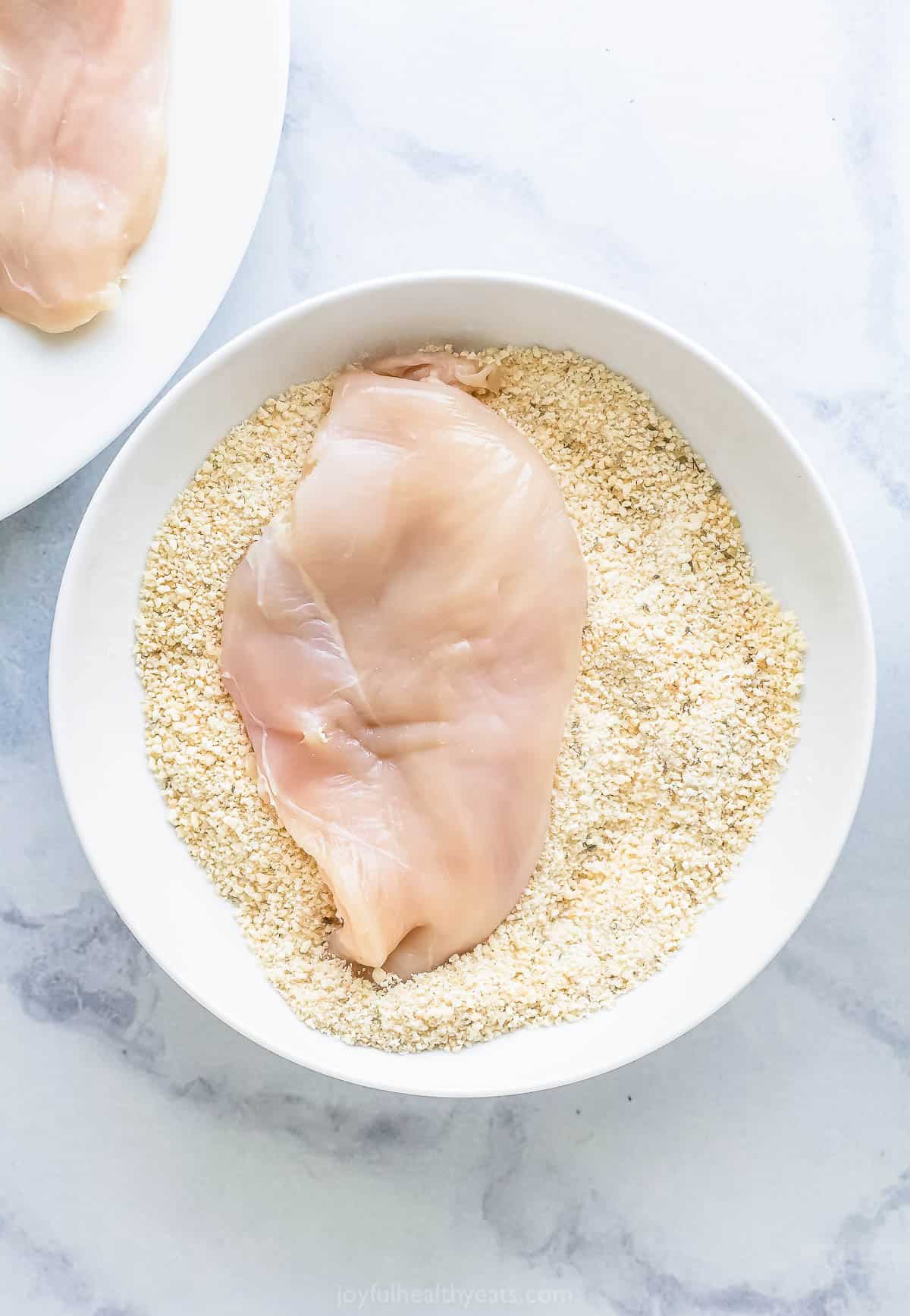 Dredging the chicken in the breading mixture. 