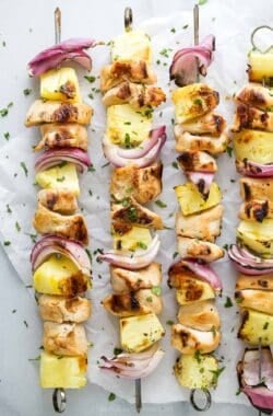 Overhead view of grilled chicken pineapple kabobs on parchment paper