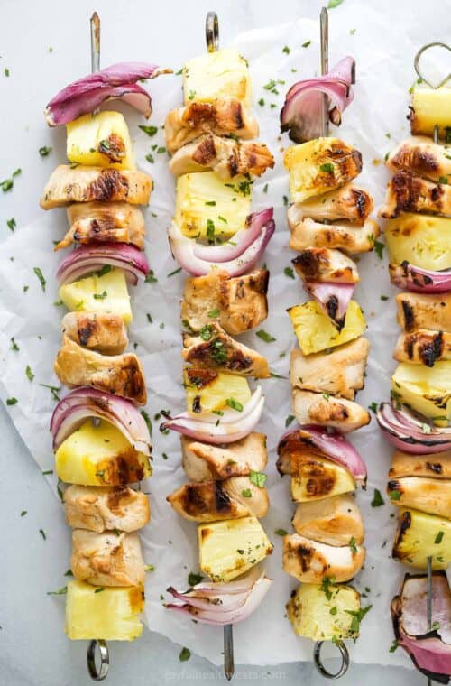 Overhead view of grilled chicken pineapple kabobs on parchment paper