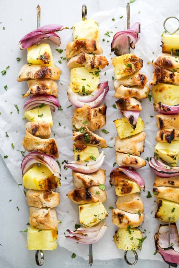 Overhead view of grilled chicken pineapple kabobs on parchment paper