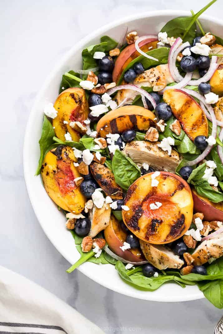 A white bowl with chicken salad and peaches