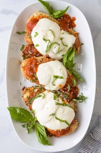 Three pieces of baked chicken parmesan on a plate.