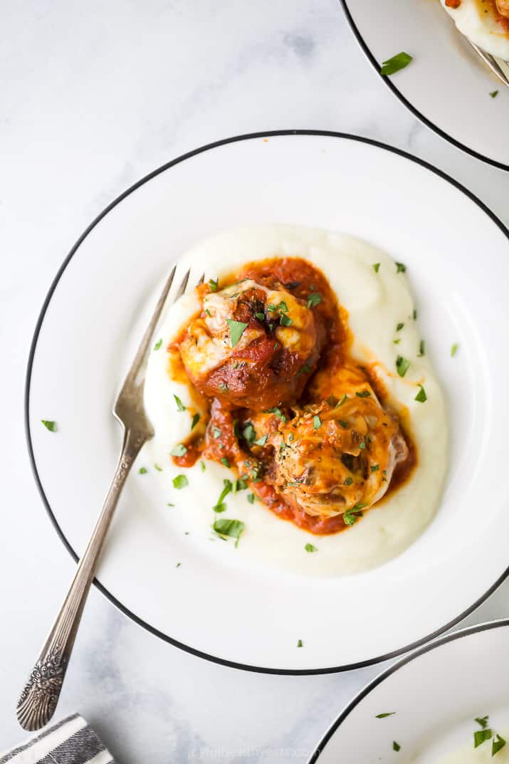 close up photo of cheesy keto turkey meatballs on top of cauliflower puree on a plate