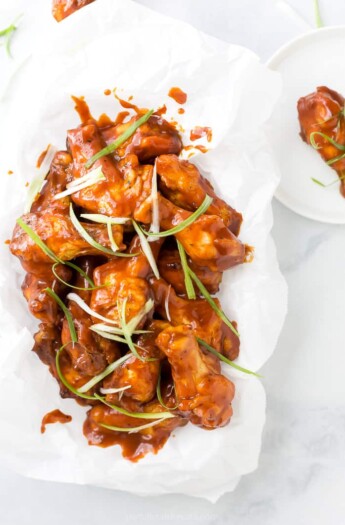 baked sweet and spicy bbq chicken wings in a basket with green onions