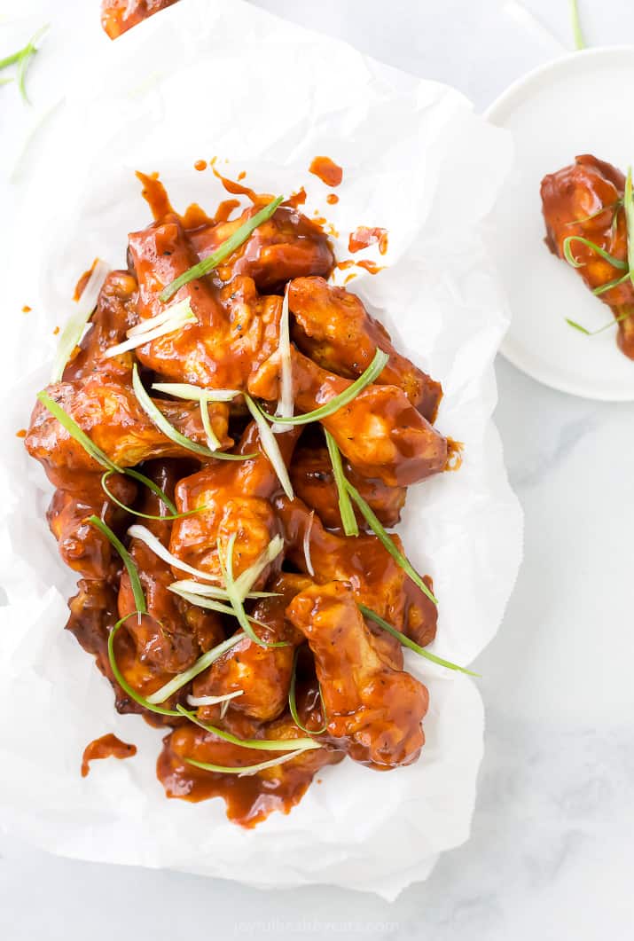 baked sweet and spicy bbq chicken wings in a basket with green onions