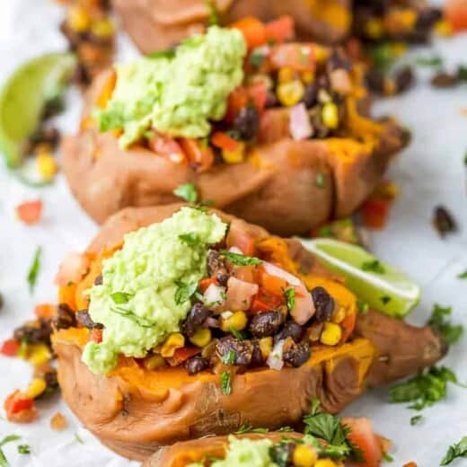 side photo of easy vegan black bean stuffed sweet potatoes with guacamole on top