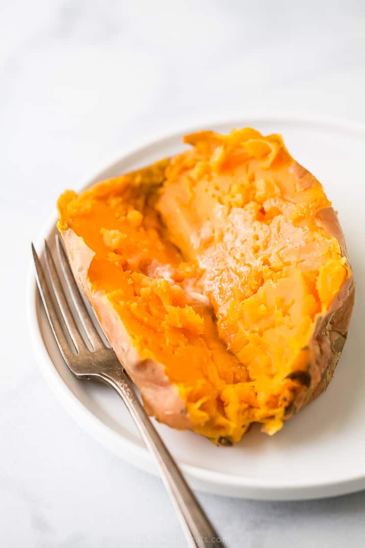 Sweet potatoes cooked in an instant pot on a plate with butter and a fork.