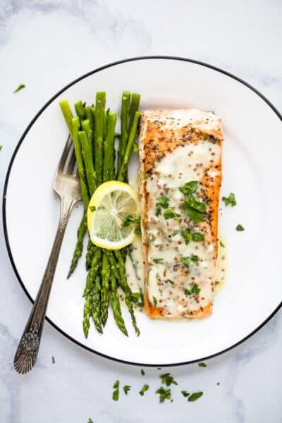 pan seared salmon with creamy dijon sauce on a plate with asparagus