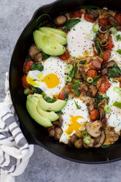 spinach mushroom breakfast skillet with eggs topped with avocado