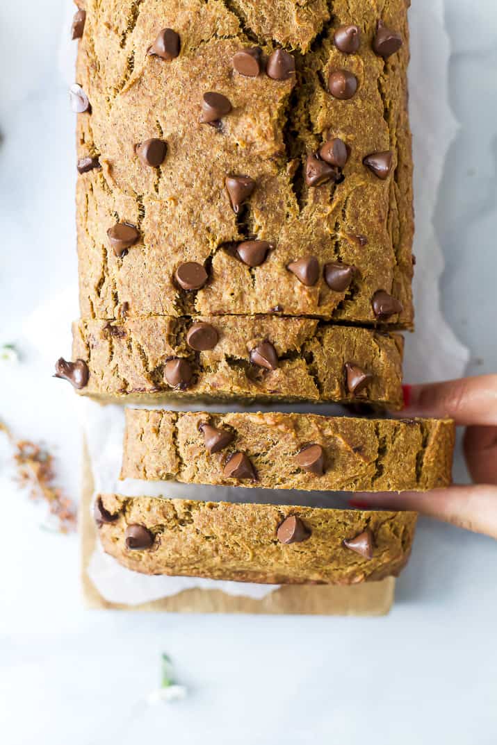 hand grabbing a slice of healthy banana pumpkin bread with chocolate chips