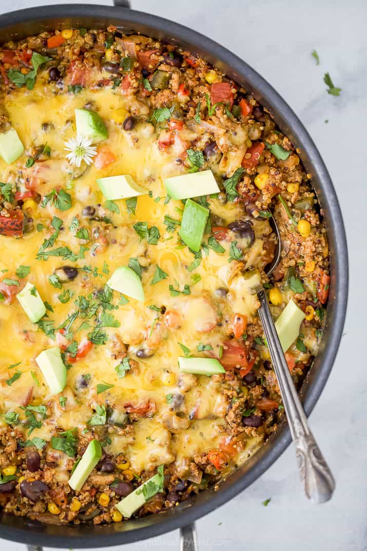 close up photo of healthy one pan cheesy quinoa taco skillet with a spoon in the pan