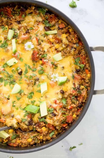 healthy one pan cheesy quinoa taco skillet topped with avocado