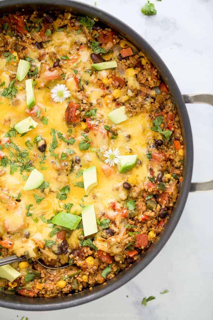 healthy one pan cheesy quinoa taco skillet topped with avocado