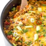 a wooden spoon taking a scoop out of healthy one pan cheesy quinoa taco skillet