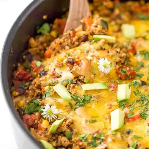 a wooden spoon taking a scoop out of healthy one pan cheesy quinoa taco skillet