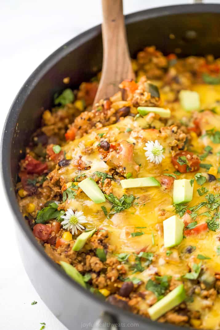 a wooden spoon taking a scoop out of healthy one pan cheesy quinoa taco skillet