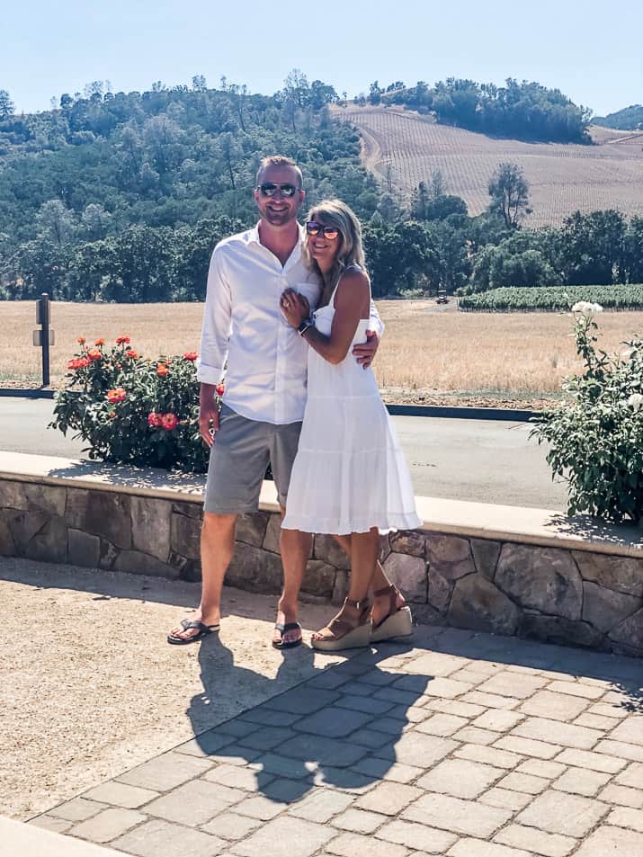 top 5 wineries in california's wine country - a couple taking a photo in front of a vineyard