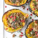 overhead photo of apple sausage stuffed acorn squash with pomegranate on top
