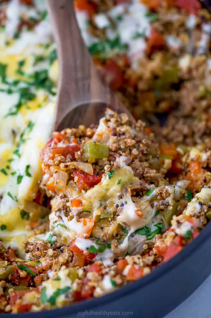 a wooden spoon scooping a one pot quinoa stuffed pepper casserole