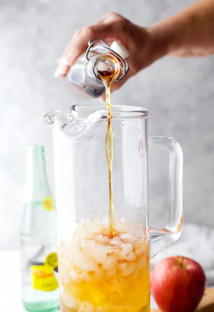 pouring bourbon into harvest apple bourbon cocktail