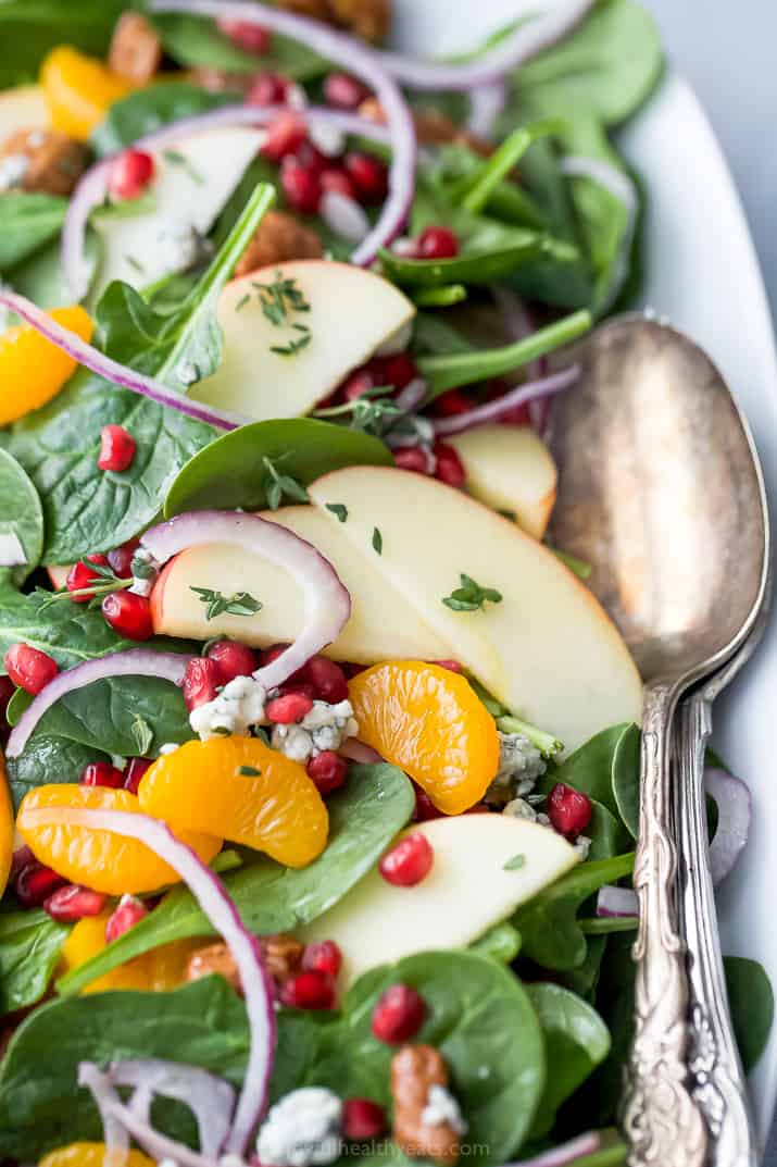 close up best spinach salad with apple pecan and gorgonzola cheese on a plate with a spoon